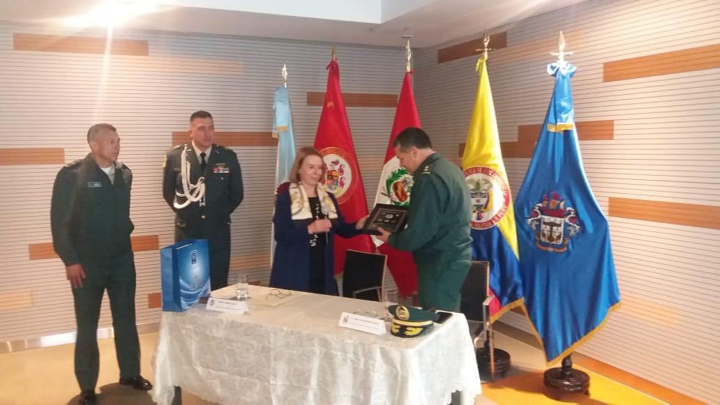 El coronel Pedro Nel Buitrago Avella entrega una placa conmemorativa durante un acto protocolario con banderas de Colombia y Perú