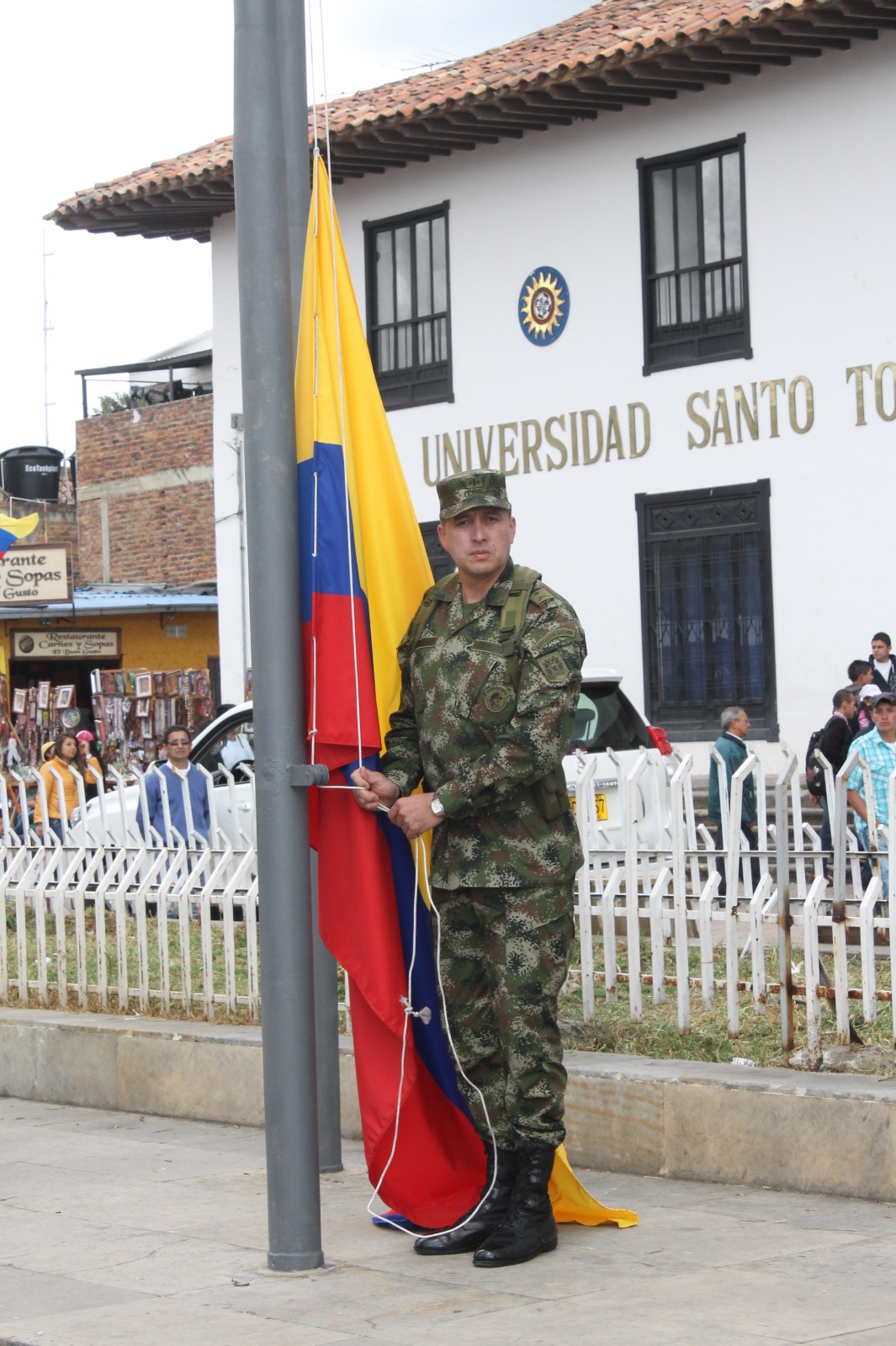 El coronel Pedro Nel Buitrago Avella iza la bandera de Colombia durante un acto cívico en el centro histórico de una ciudad