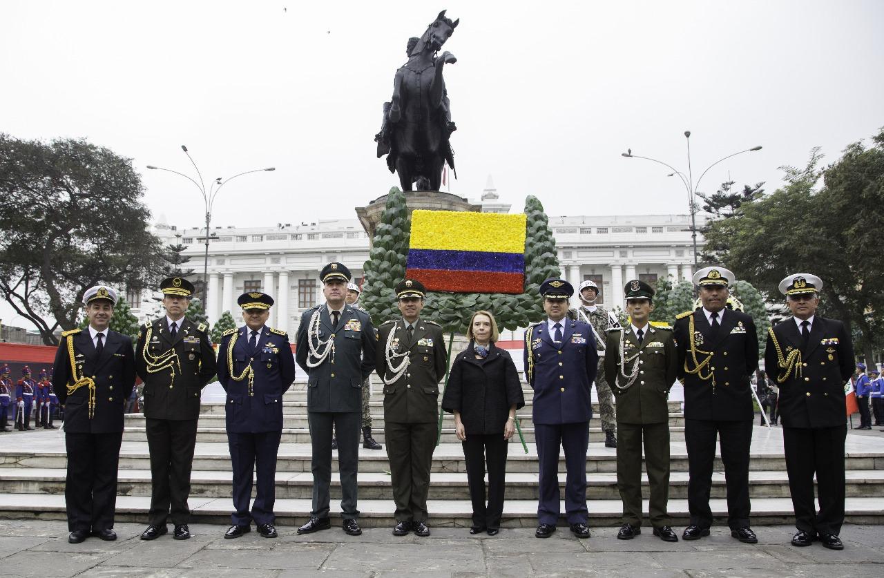 Oficiales de las Fuerzas Militares y de Policía de Colombia junto a una ofrenda floral ante el monumento a Simón Bolívar en Lima